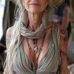 Smiling woman in bohemian attire, wearing large hat.