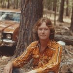 Man in orange plaid shirt outdoors by truck
