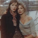 Two women sitting outdoors with intertwined branches.