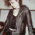 Person in leather jacket and pants, edgy hairstyle.