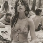 Woman sitting outdoors wearing crochet top and accessories.