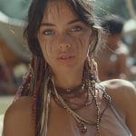 Young woman with face paint and beads outdoors.