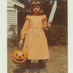 Child in costume holding pumpkin and large knife