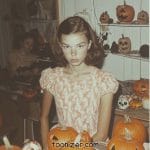Girl surrounded by carved Halloween pumpkins.