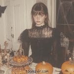 Woman in black dress with Halloween decorations.