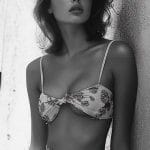 Person in floral outfit leaning against wall