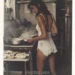 Woman cooking in vintage kitchen, wearing lace outfit.