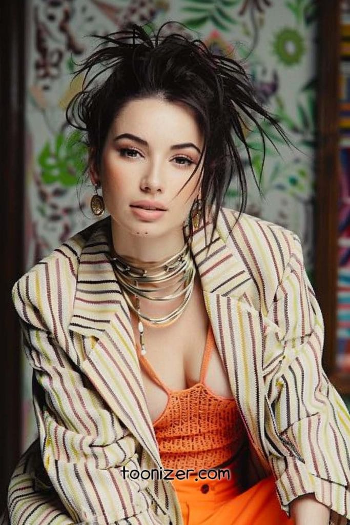 Woman in striped jacket with necklaces, colorful background.