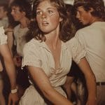 Young woman dancing energetically at crowded event.