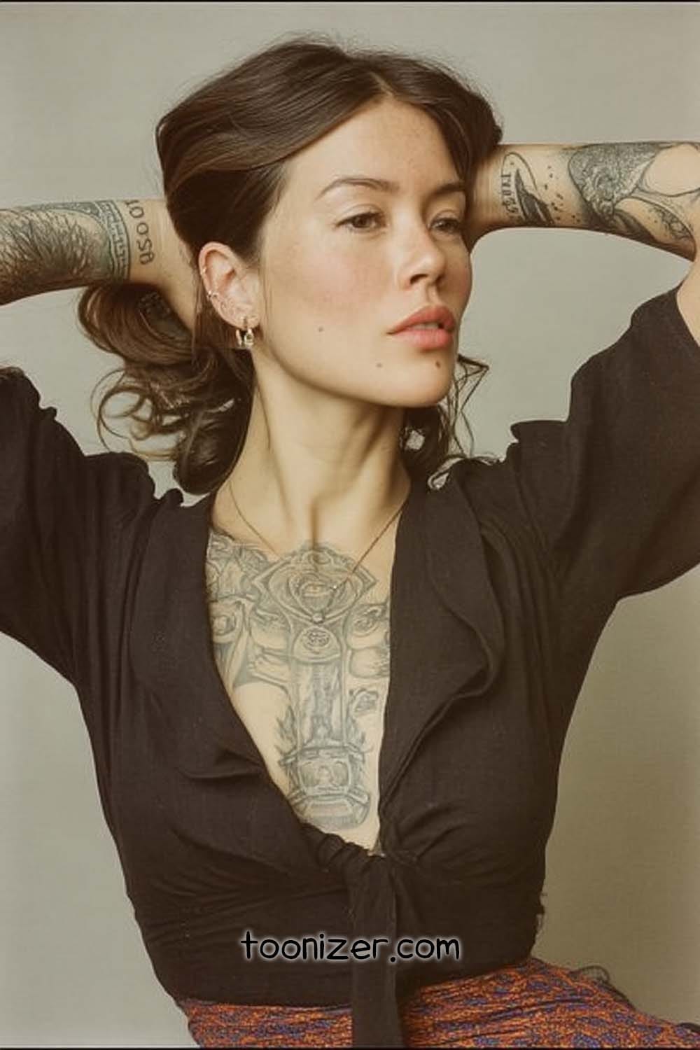 Tattooed woman posing with arms raised