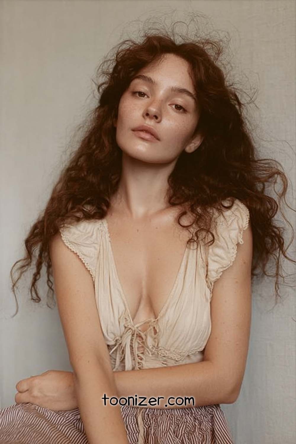 Young woman with curly auburn hair posing indoors