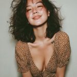 Smiling woman wearing patterned dress and tousled hair.