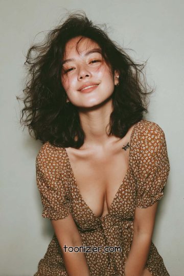 Smiling woman wearing patterned dress and tousled hair.