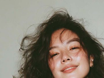 Smiling woman wearing patterned dress and tousled hair.