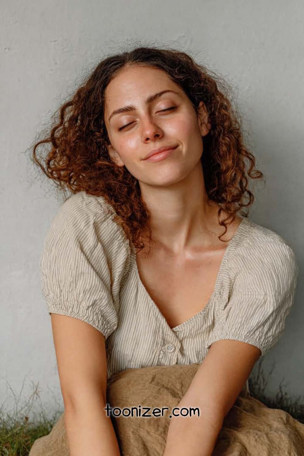 Woman with curly hair smiling peacefully.