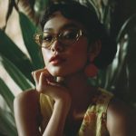 Woman with glasses in a tropical setting.