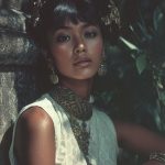 Woman in traditional attire near stone wall