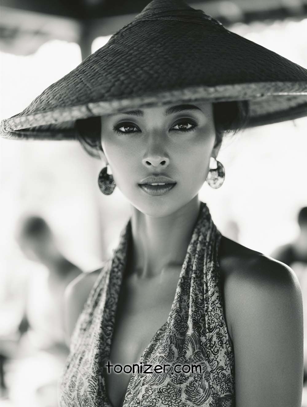 Woman wearing traditional conical hat, black-and-white portrait.
