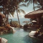 Tropical poolside with palm trees and ocean view.