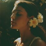 Woman with flowers in hair, outdoor sunlight scene.