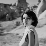 Monochrome portrait of a woman in scenic landscape.