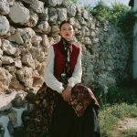 Woman in traditional dress by stone wall