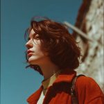Woman in orange jacket against blue sky