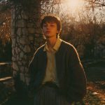 Young person in rustic setting during sunset.