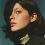 Woman with shadowed face under blue sky.