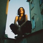 Person squatting on rooftop at sunset