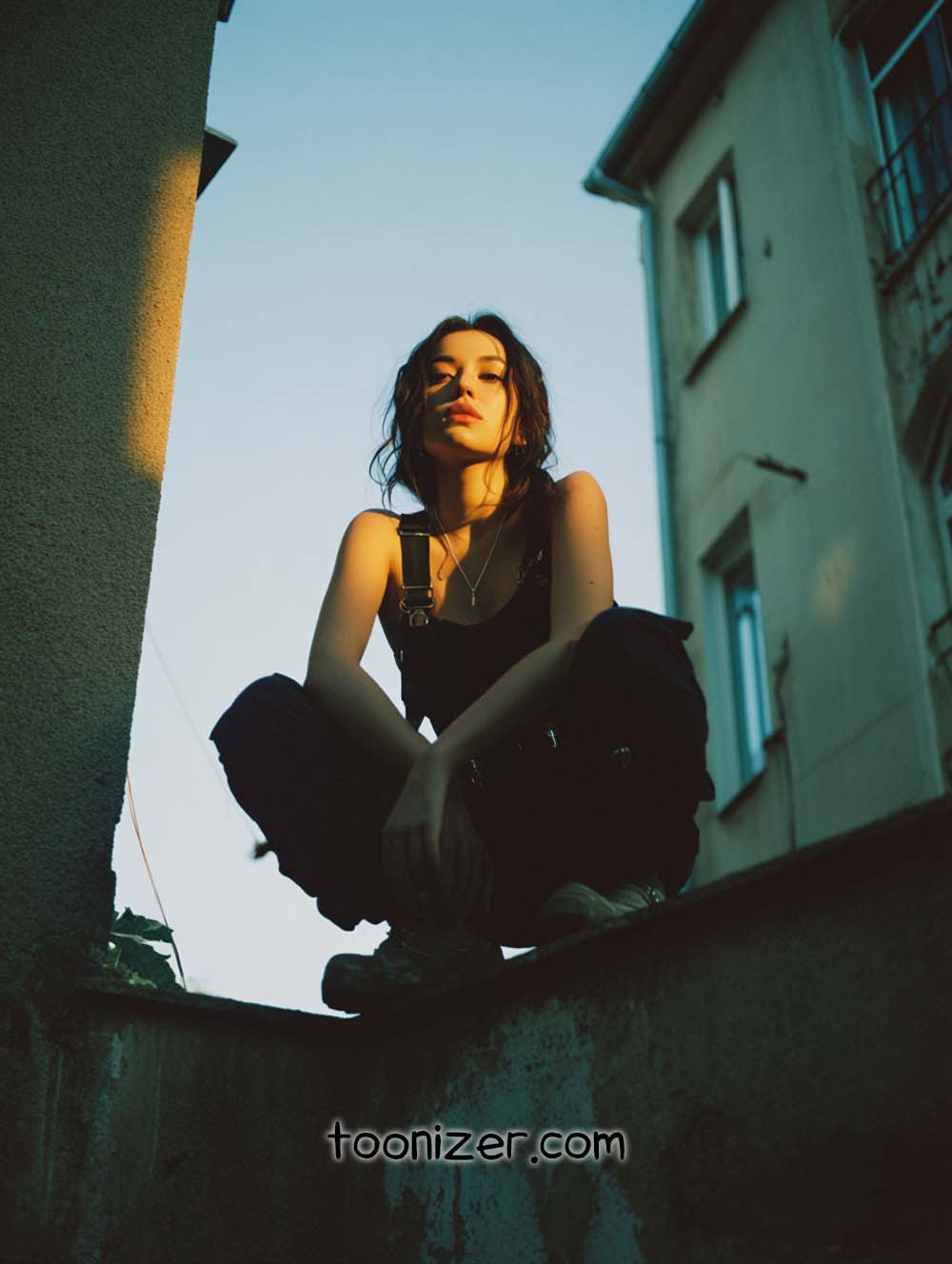 Person squatting on rooftop at sunset