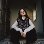 Person sitting on colorful tiled stairs indoors.