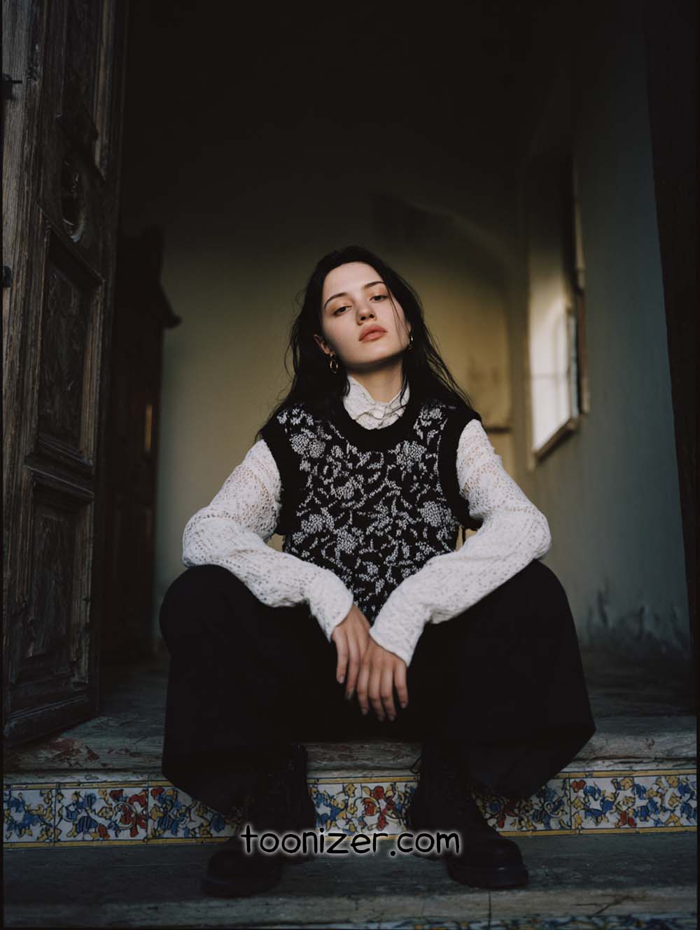 Person sitting on colorful tiled stairs indoors.