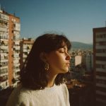 Woman enjoying sunlight on urban balcony