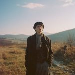 Person standing in field with mountains background.