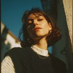 Person basking in sunlight, wearing knit sweater.