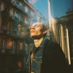 Person basking in sunlight by urban building.