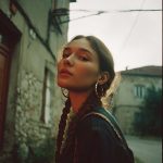 Person with braids in urban setting, sunset backdrop.