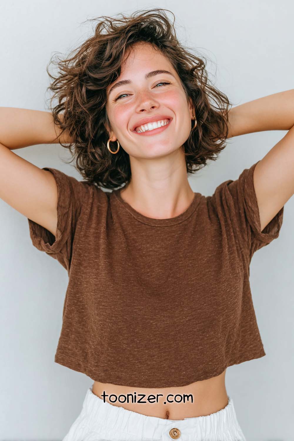 Smiling woman in brown top with arms raised.