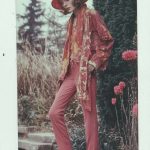 Person in vintage red outfit and hat outdoors.