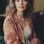 Woman with wavy hair in patterned shirt, serene expression.