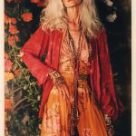 Elegant woman in floral dress with flowers backdrop.