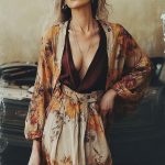 Woman in floral attire near a car.