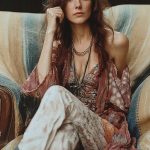 Woman in colorful bohemian outfit sitting thoughtfully.