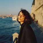 Person standing by water on a sunny day.