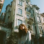 Person standing by old European building in sunlight.