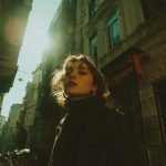 Woman in city street under bright sunlight