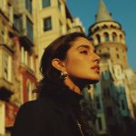 Person near historical tower in urban setting.