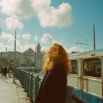 Person standing on bridge with cityscape background.