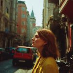 Woman in yellow coat walking in sunlit street